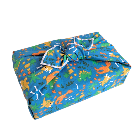 Gift wrapped in a reusable furoshiki wrapping cloth with a roaming dinosaur print