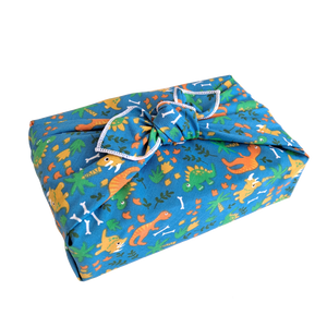 Gift wrapped in a reusable furoshiki wrapping cloth with a roaming dinosaur print