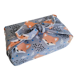 Gift wrapped in a furoshiki (reusable wrapping cloth) with a blushing foxes print on a grey background