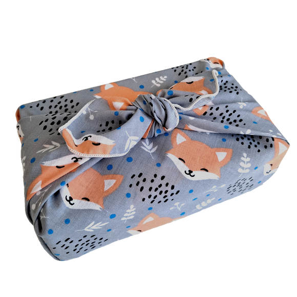 Gift wrapped in a furoshiki (reusable wrapping cloth) with a blushing foxes print on a grey background
