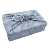 Gift wrapped in a furoshiki with a delicate feather pattern on silvery grey